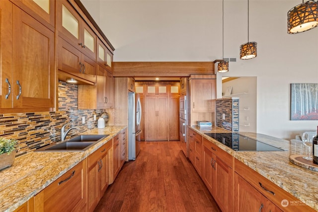 kitchen with sink, light stone counters, pendant lighting, stainless steel appliances, and decorative backsplash