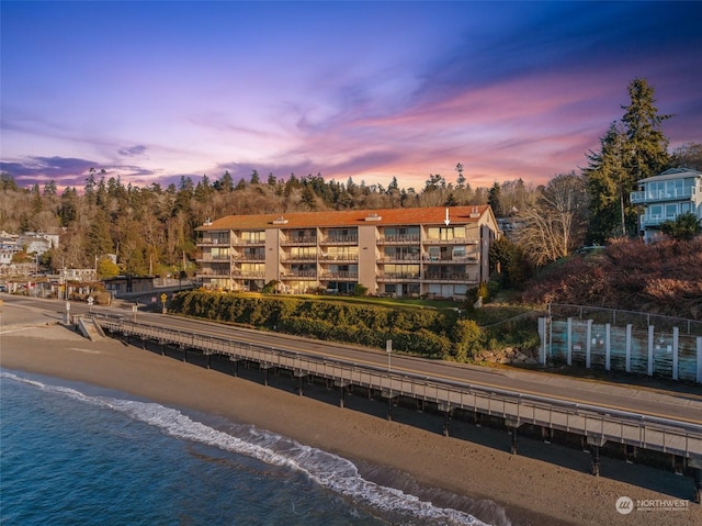 outdoor building at dusk with a water view and a view of the beach