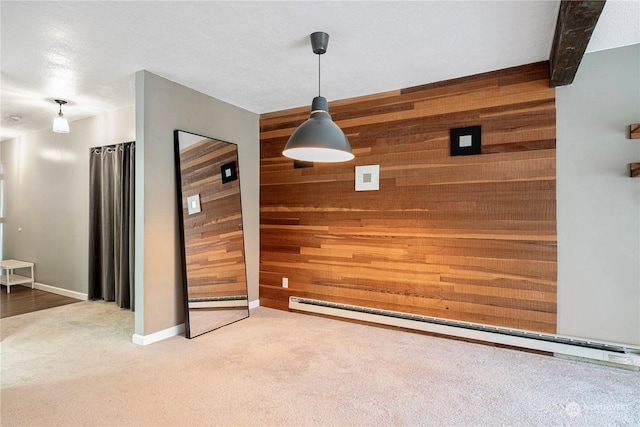 unfurnished dining area featuring wooden walls, beam ceiling, carpet, and a baseboard heating unit