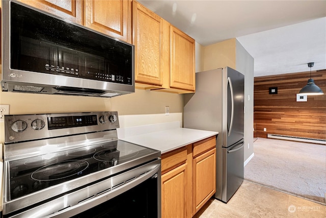 kitchen with wooden walls, decorative light fixtures, a baseboard heating unit, light colored carpet, and stainless steel appliances