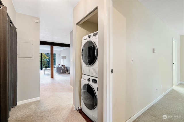 laundry room featuring stacked washer and dryer and light carpet