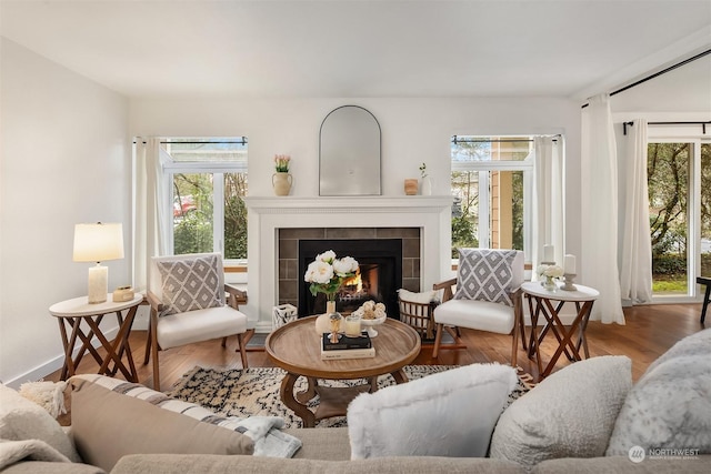 sitting room featuring a tile fireplace, plenty of natural light, and wood-type flooring