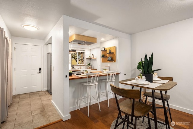 interior space featuring stainless steel fridge, wooden counters, a kitchen breakfast bar, kitchen peninsula, and light wood-type flooring