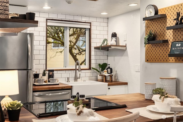 kitchen with butcher block counters, sink, stainless steel fridge, decorative backsplash, and hardwood / wood-style flooring