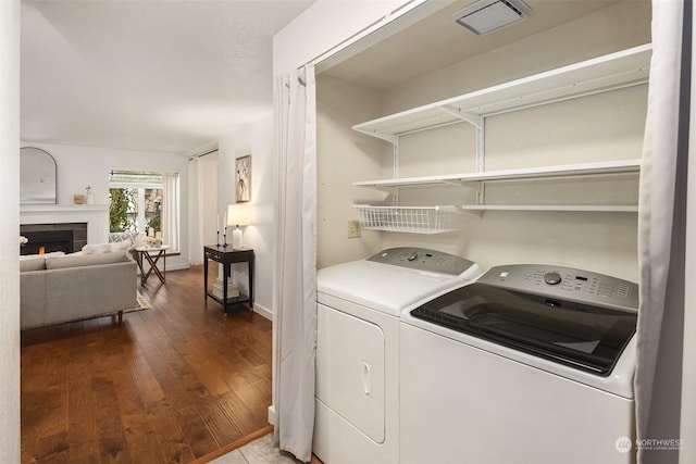 laundry room with a fireplace, dark hardwood / wood-style flooring, and washer and dryer