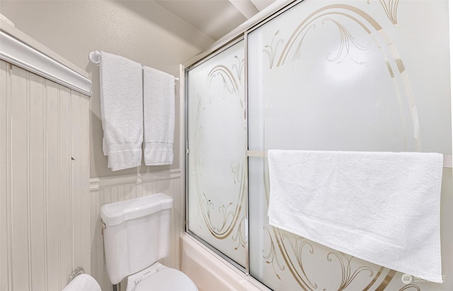 bathroom featuring bath / shower combo with glass door and toilet