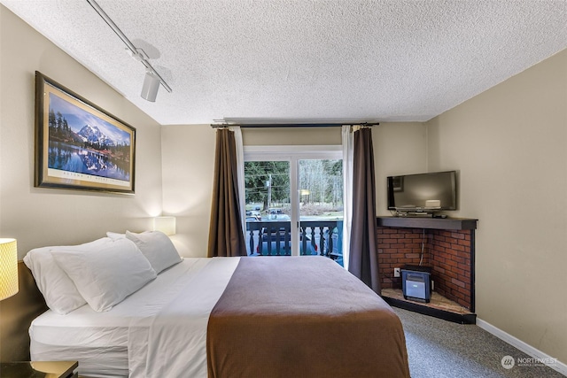 bedroom featuring rail lighting, carpet, access to exterior, and a textured ceiling