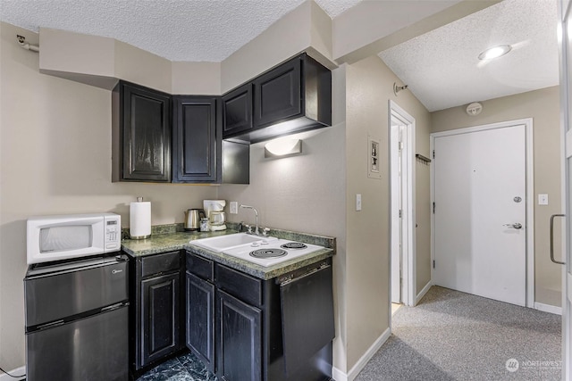 kitchen featuring sink, stainless steel refrigerator, a textured ceiling, and carpet flooring