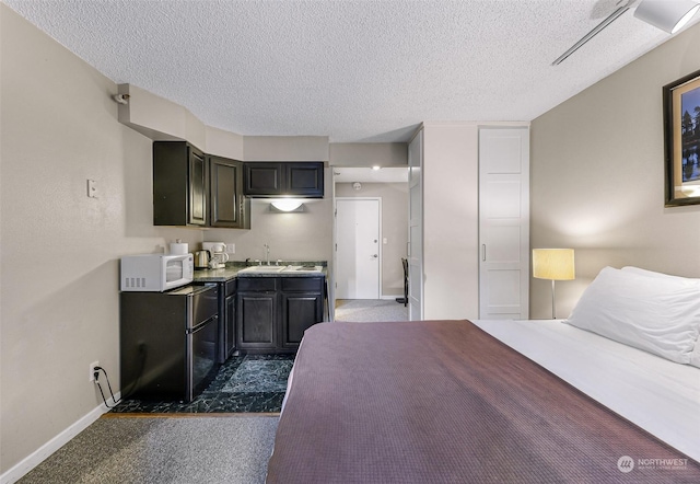 carpeted bedroom featuring ensuite bath, sink, and a textured ceiling