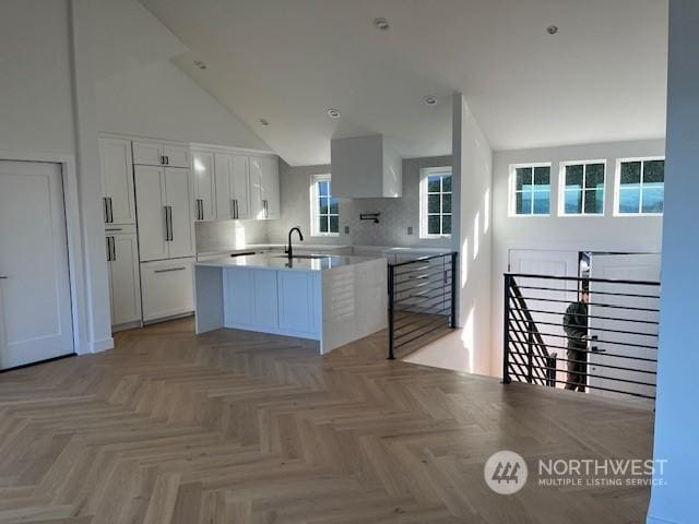 kitchen with paneled fridge, sink, light parquet floors, and white cabinets