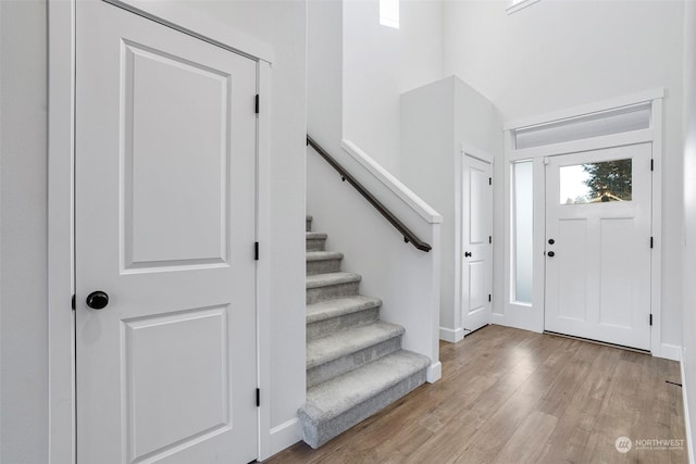 foyer entrance with a towering ceiling and light hardwood / wood-style flooring