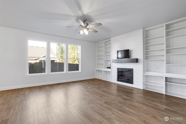 unfurnished living room featuring ceiling fan, hardwood / wood-style floors, built in features, and a fireplace