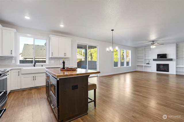 kitchen featuring a kitchen island, sink, white cabinets, a kitchen breakfast bar, and hanging light fixtures