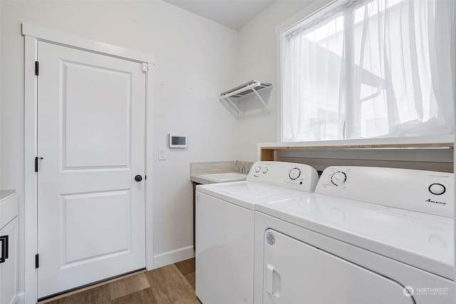 clothes washing area with sink, washer and clothes dryer, and hardwood / wood-style floors