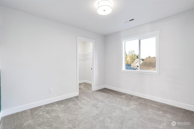 spare room featuring light carpet and a textured ceiling