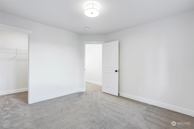 unfurnished bedroom featuring carpet, a spacious closet, and a closet