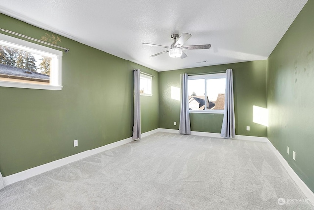 carpeted spare room featuring a textured ceiling and ceiling fan