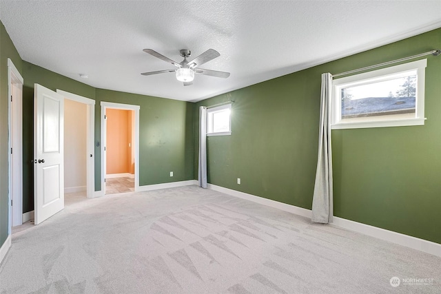 unfurnished bedroom with ceiling fan, light carpet, and a textured ceiling