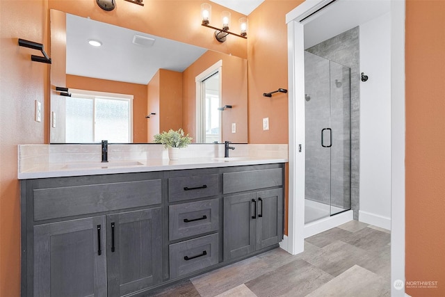 bathroom featuring a shower with door and vanity