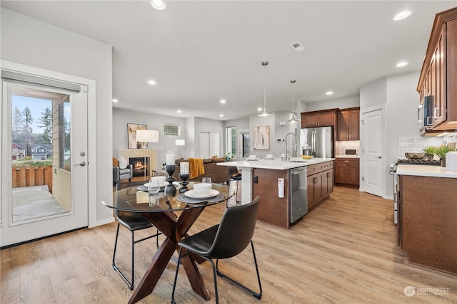 dining room featuring a tiled fireplace, sink, and light hardwood / wood-style flooring