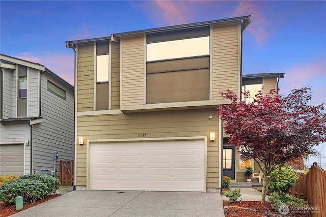 view of front of house featuring driveway, a garage, and fence