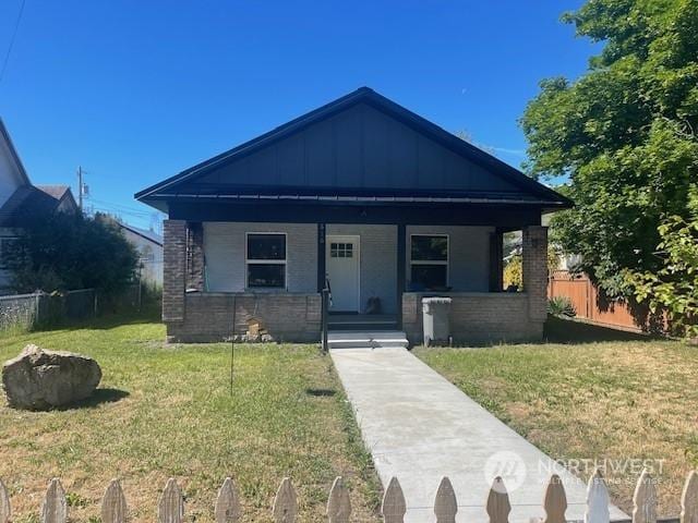 bungalow-style home with covered porch and a front yard