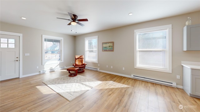 living area featuring ceiling fan, baseboard heating, and light hardwood / wood-style floors