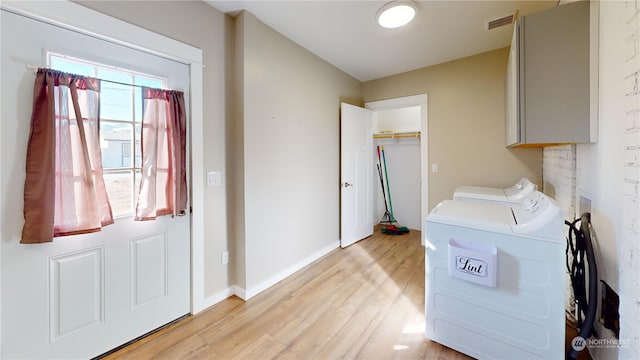 washroom with cabinets, washer and dryer, and light hardwood / wood-style floors