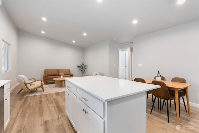 kitchen with white cabinetry, a kitchen island, and light hardwood / wood-style flooring