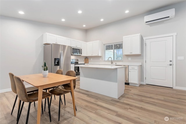 kitchen featuring a kitchen island, a wall mounted air conditioner, sink, white cabinets, and stainless steel appliances