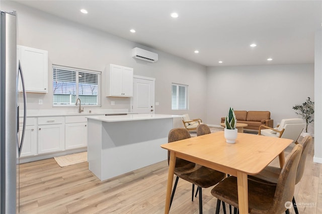 dining space with sink, a wall mounted AC, and light wood-type flooring