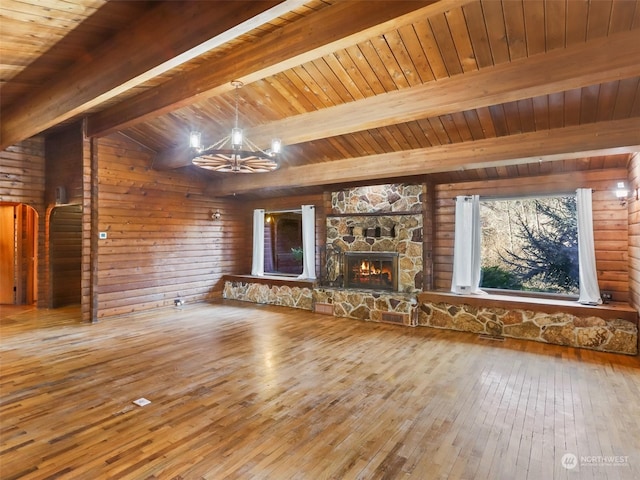 unfurnished living room featuring a stone fireplace, an inviting chandelier, wood-type flooring, wooden walls, and beamed ceiling