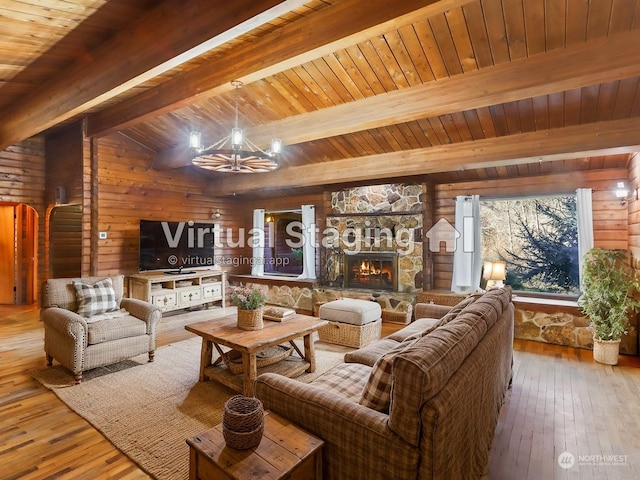 living room with a notable chandelier, hardwood / wood-style flooring, wooden walls, and a stone fireplace