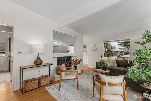 living room featuring a fireplace, beamed ceiling, and light wood-type flooring