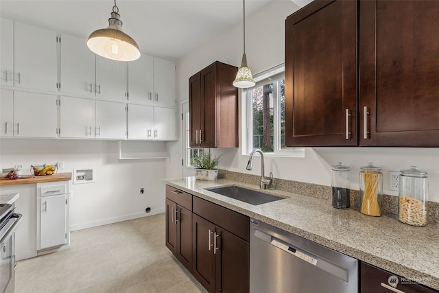 kitchen featuring pendant lighting, sink, dark brown cabinets, stainless steel appliances, and light stone counters