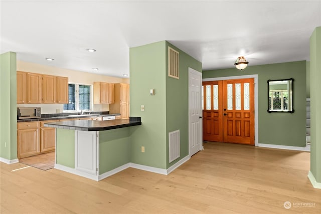 kitchen with sink, light hardwood / wood-style flooring, kitchen peninsula, and light brown cabinets