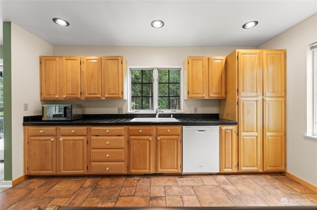 kitchen with white dishwasher, sink, and light brown cabinetry