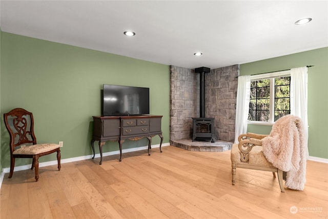 sitting room featuring light wood-type flooring and a wood stove