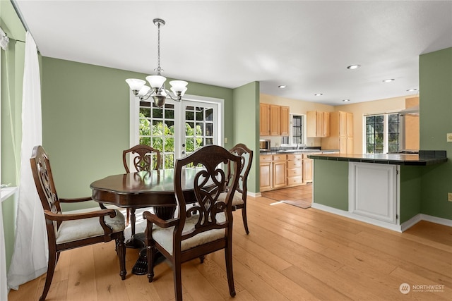 dining area with sink, an inviting chandelier, and light hardwood / wood-style flooring