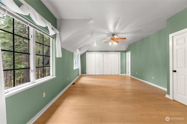 unfurnished bedroom with a closet, lofted ceiling, ceiling fan, and light hardwood / wood-style flooring