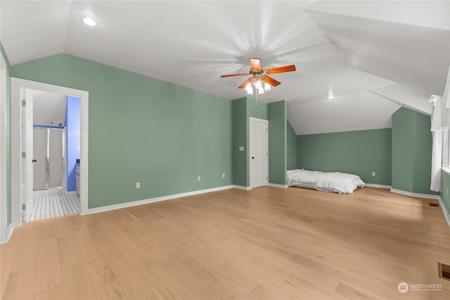 unfurnished bedroom featuring ensuite bath, light hardwood / wood-style flooring, ceiling fan, and vaulted ceiling