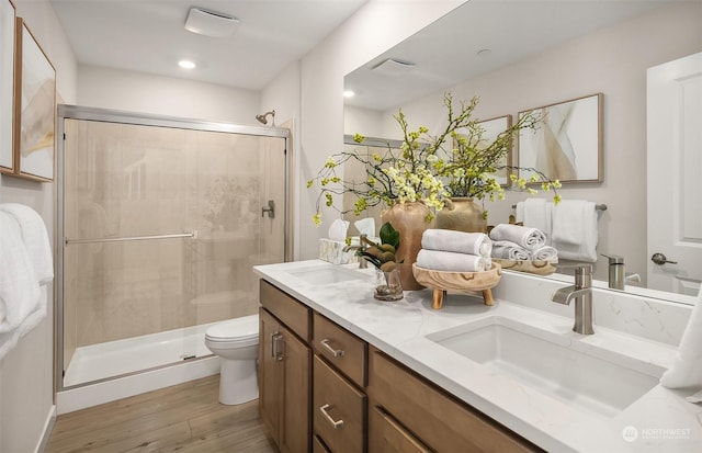 bathroom featuring vanity, hardwood / wood-style flooring, a shower with shower door, and toilet