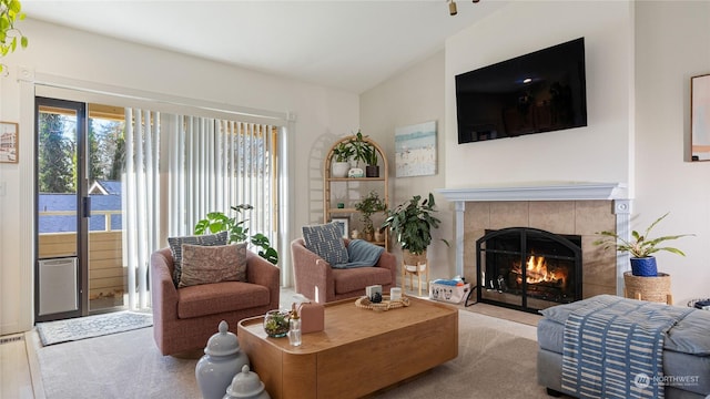 carpeted living room with vaulted ceiling and a tile fireplace