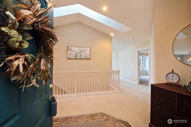 hallway with lofted ceiling with skylight and light carpet