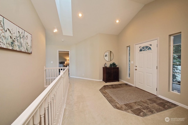 carpeted foyer entrance featuring high vaulted ceiling