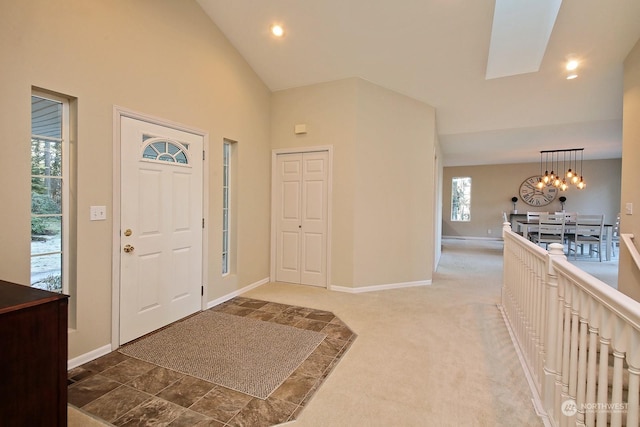 carpeted entrance foyer featuring high vaulted ceiling and a chandelier