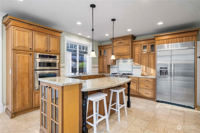 kitchen with pendant lighting, sink, a center island, light stone counters, and stainless steel appliances