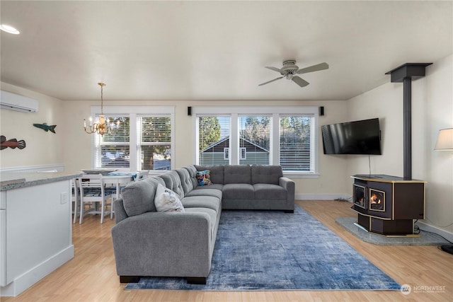 living room featuring a healthy amount of sunlight, a wall mounted AC, light hardwood / wood-style flooring, and a wood stove