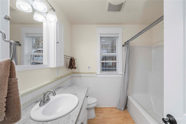 full bathroom featuring wood-type flooring, tile walls, vanity, toilet, and shower / bathtub combination with curtain