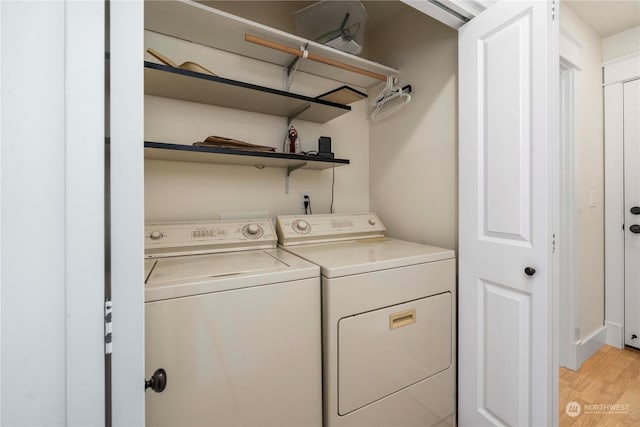 laundry room with washing machine and clothes dryer and light hardwood / wood-style floors